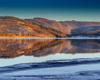 Scenic view of lake by mountains against sky