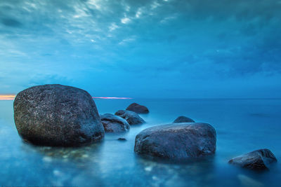Rocks in sea against blue sky