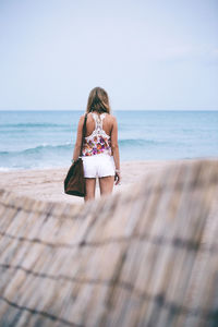 Rear view of woman on beach against sky