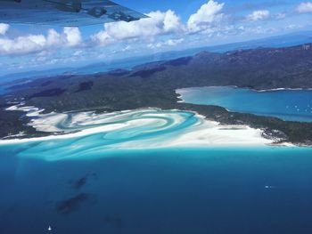 Aerial view of sea and mountains against blue sky