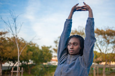 Portrait of beautiful young woman standing against sky