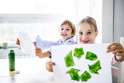 Girl holding paper with painted recycling symbol