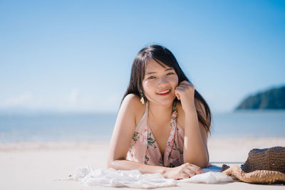 Portrait of woman sitting on beach against sky