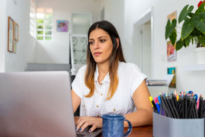 Portrait of young woman using phone while sitting on table