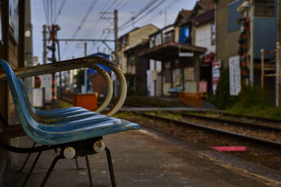 Empty bench by railroad tracks in city