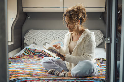 Woman reading book sitting in camper van