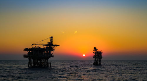 Silhouette ship in sea against sky during sunset