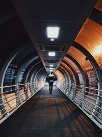 Rear view of man levitating at illuminated covered bridge