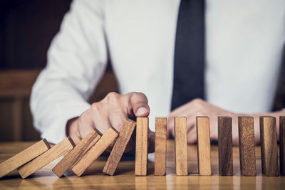 Midsection of businessman playing with wooden dominoes at desk