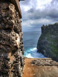 Close-up of cliff by sea against sky