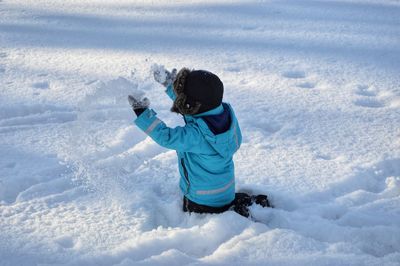 Boy playing with snow on road