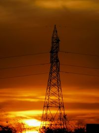 Low angle view of silhouette electricity pylon against sky during sunset