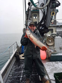 Portrait of smiling man holding fish while standing in boat