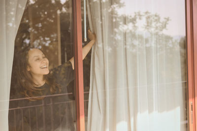 Young woman looking through window