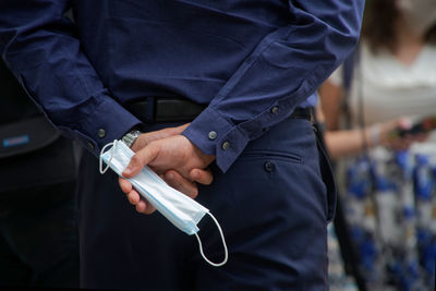 Midsection of man holding mask while standing outdoors