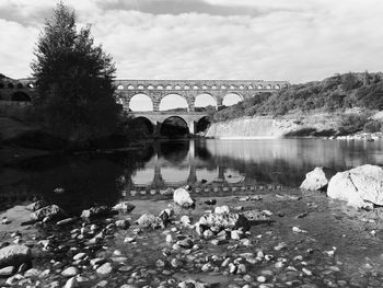 Arch bridge over river against sky in city