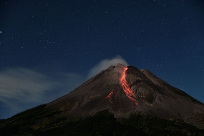 Light trails on mountain against sky at night