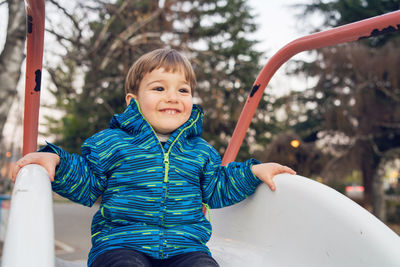 Cute boy playing on slide at playground