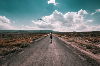 Rear view of woman running on road against sky