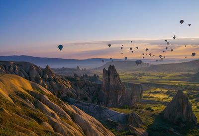 Hot air balloons flying over mountain landscape against sky