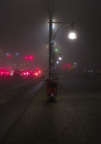 Illuminated street light on road in city at night