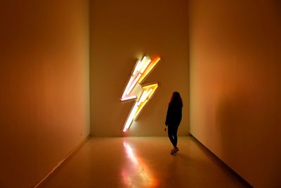 Silhouette woman standing against illuminated sign in room