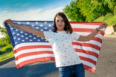 Portrait of smiling pretty young woman holding waving american flag. usa celebrate 4th of july. 