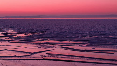 Scenic view of frozen sea against orange sky during sunset