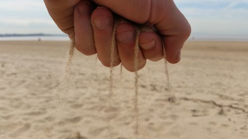 Close-up of hand holding sand at beach