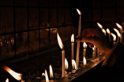 Human hand holding lit candles in temple