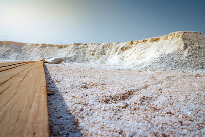 Low angle view of brine salt farm with blue sky. pile of organic sea salt near warehouse. 