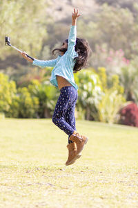 Full length of woman jumping on field