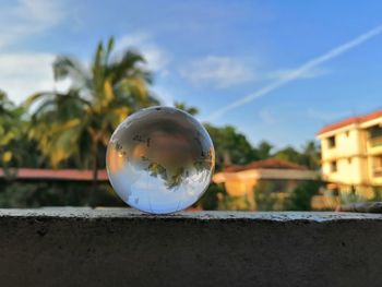 Close-up of crystal ball on glass building against sky