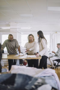 Smiling male and female fashion designers communicating with each other at workshop