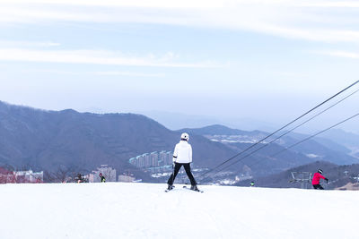 Rear view of man skiing on snowcapped mountain against sky