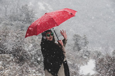 Woman with umbrella standing in snow during rainy season