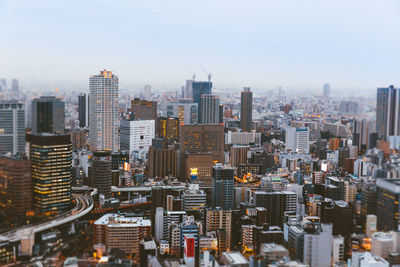 Aerial view of illuminated cityscape against sky during sunset