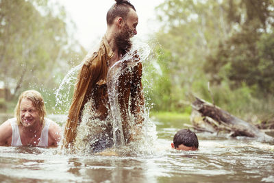 Happy friends bathing in river at forest