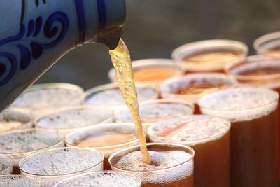 Close-up of jug pouring apple juice in drinking glass