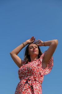 Low angle view of woman standing against blue sky