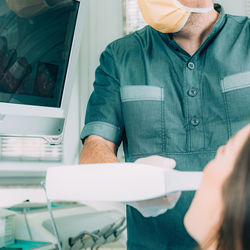 Midsection of dentist examining patient teeth