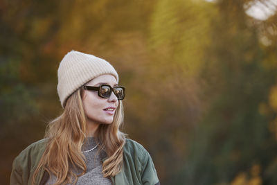 Portrait of young woman standing against trees