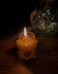 Close-up of lit candle on table against black background
