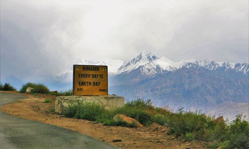 Road sign on landscape against sky