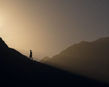 Silhouette man standing on mountain against sky during sunset