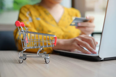 Midsection of man using mobile phone while sitting on table