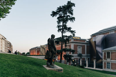 Statue by houses against clear sky