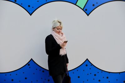 Low angle view of woman standing against blue sky