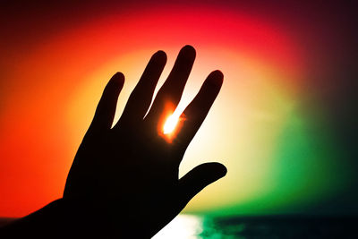 Close-up of human hand against orange sky
