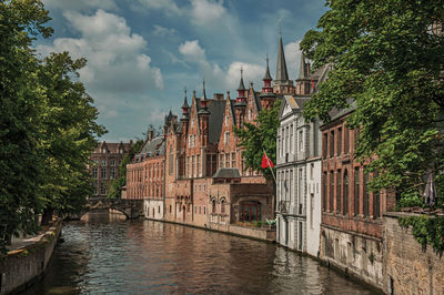 Gardens and brick buildings on the canal edge in bruges. a town full of canals in belgium.